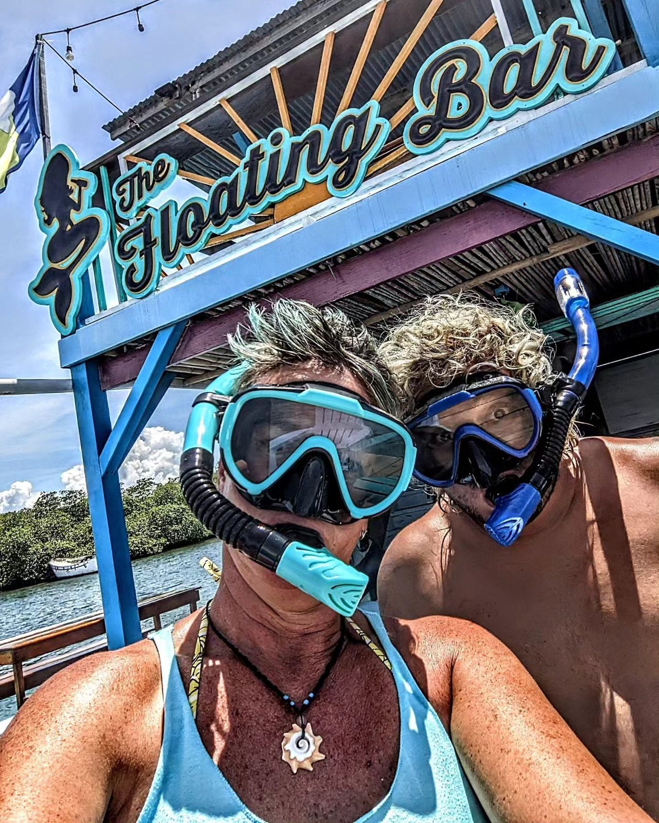 Two snorkelers in masks under The Floating Bar sign